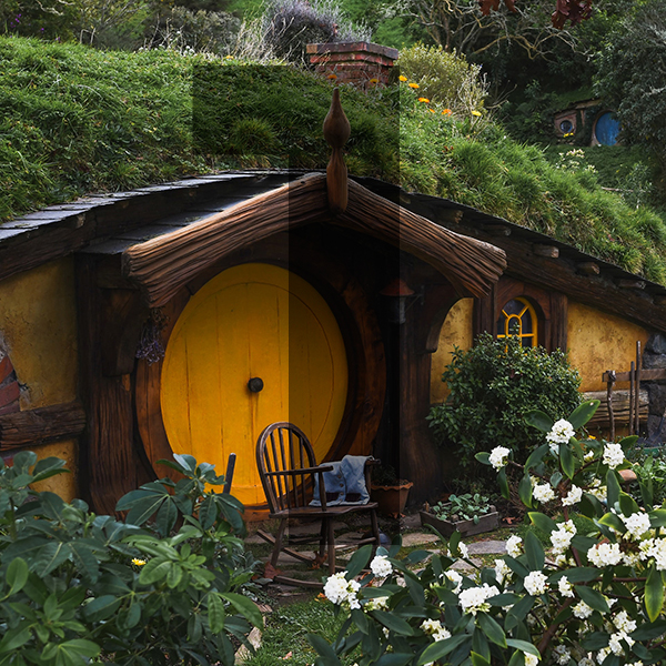 A Hobbit style house built into the side of a hill with a yellow door