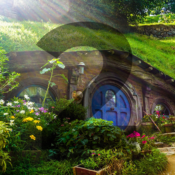 A Hobbit style house built into the side of a hill with a blue door